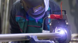 Handwerker mit Schutzausrüstung beim Schweißen eines Rohrs.