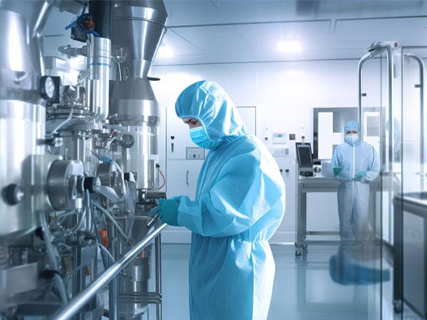 Mitarbeiter in blauen Schutzanzügen und Masken arbeiten in einem Reinraumlabor mit moderner technischer Ausrüstung.